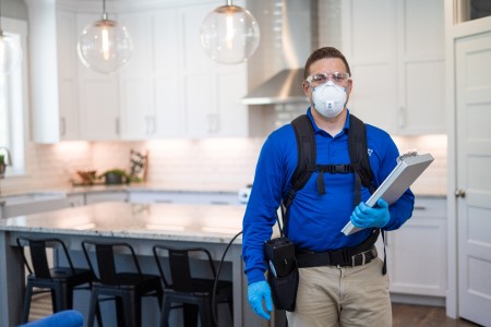technician standing in front of kitchen with a mask on